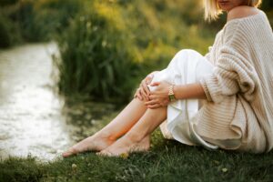 Femme sereine assise dans l'herbe au bord de l'eau – ménopause et sexualité épanouie